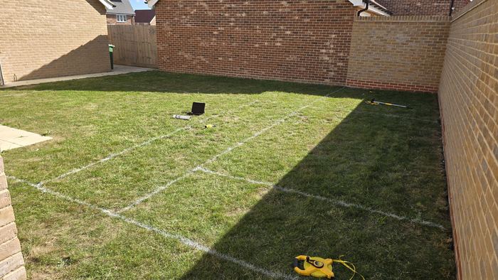 A new build garden marked out with line paint, viewed from the house